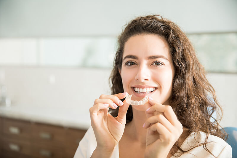 Woman Putting in Clear Dental Aligners